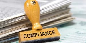 Compliance rubber stamp leaning against several files